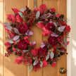 Deep red foliage and pumpkin Christmas wreath by Heaven Sends, styled for holiday decor with autumnal accents.