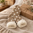 Beige polka dot fleece-lined slipper socks styled beside a kraft gift box