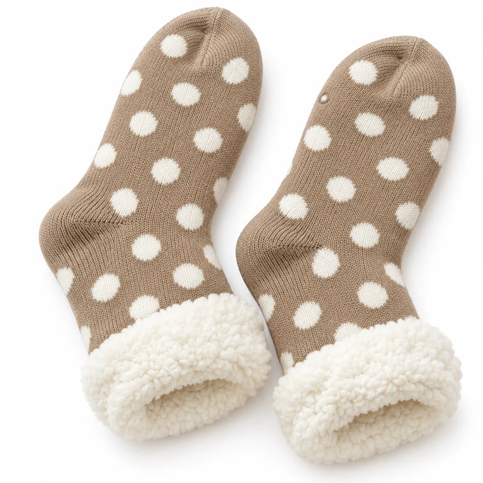 Pair of beige and cream polka dot fleece-lined slipper socks on white