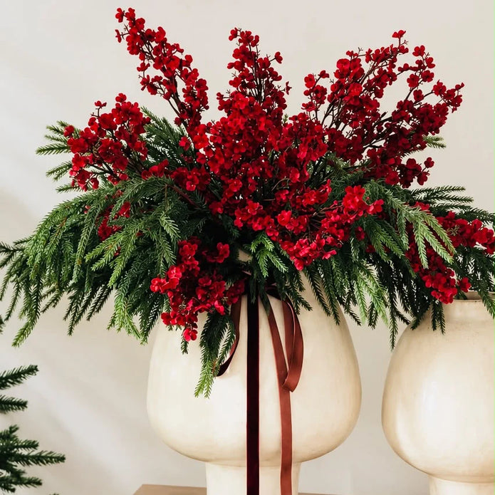 Burgundy gypsophila stems mixed with evergreen foliage in a cream footed vase.