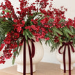 Close-up of burgundy gypsophila flowers amongst evergreen foliage in a cream vase.