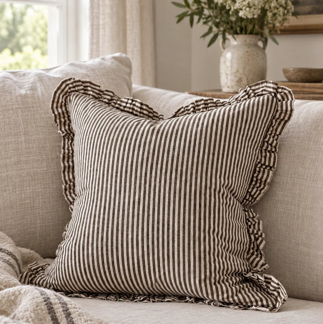 Darcy chocolate brown and white pinstripe 45cm cushion cover styled on a neutral sofa