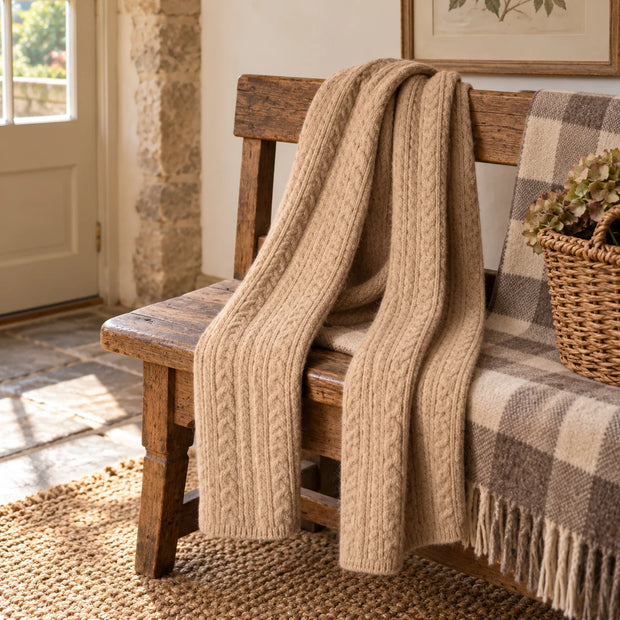 Oatmeal cable knit scarf draped over a rustic wooden bench