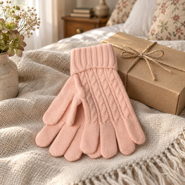 Pink cable knit gloves styled beside a kraft gift box