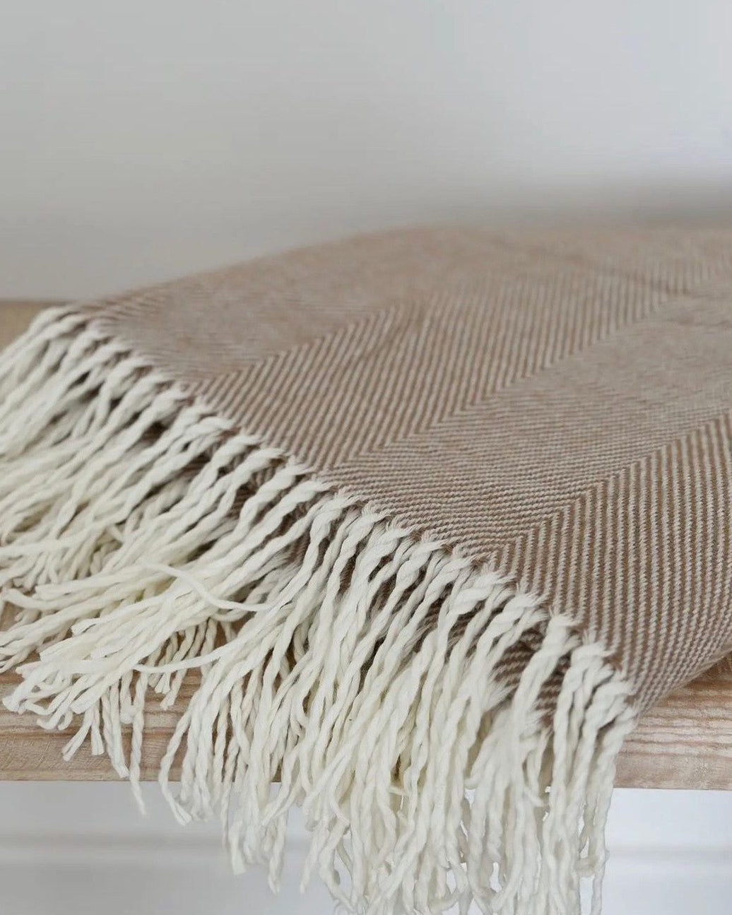 Beige herringbone throw blanket with brown tassels from Ellenvale Trade, soft furnishings for cozy decor.