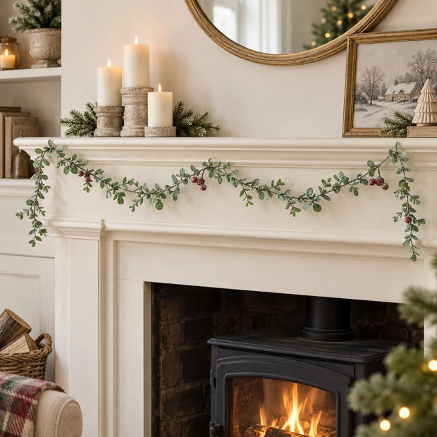 Eucalyptus And Red Berry Garland draped along a cream mantel.