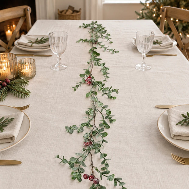 Eucalyptus And Red Berry Garland along a linen Christmas table.