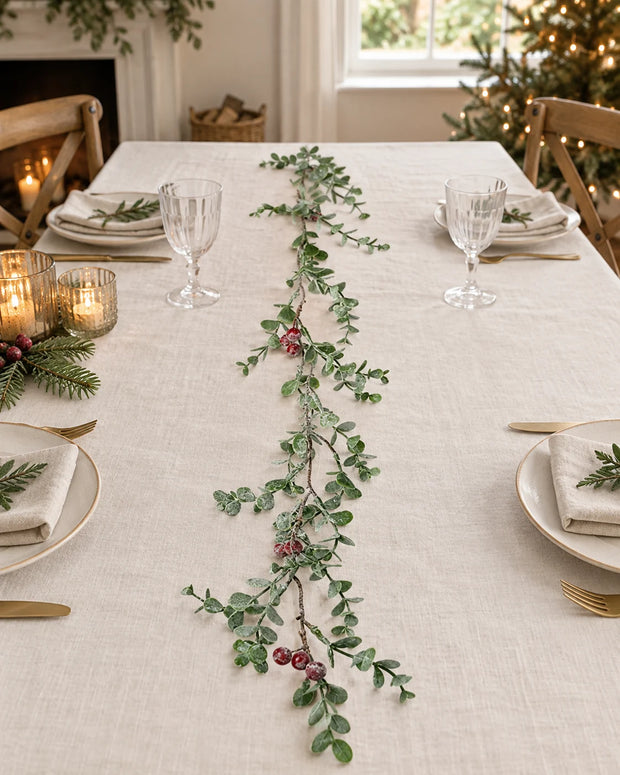Eucalyptus And Red Berry Garland along a linen Christmas table.