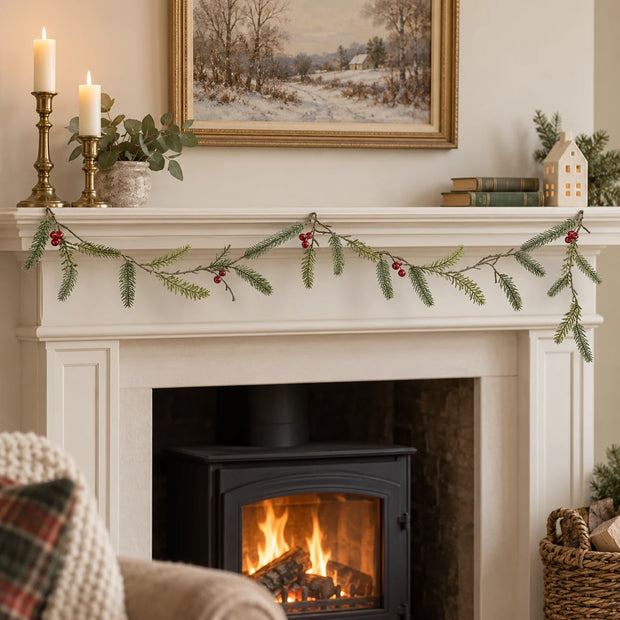 Green Fir And Red Berry Garland draped along a cream mantel.