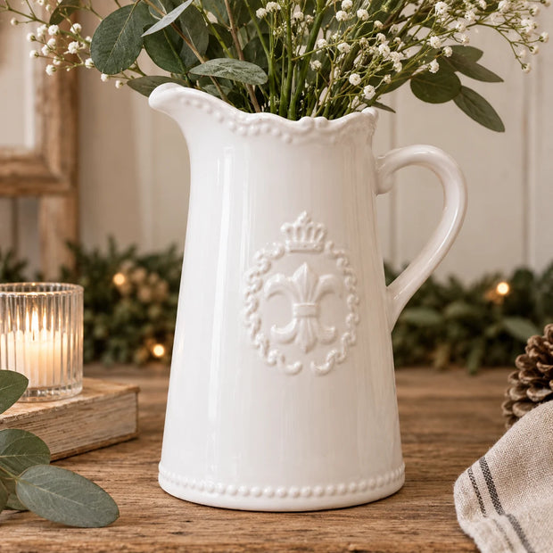 White Fleur de Lis ceramic jug filled with eucalyptus and white flowers styled on rustic wooden country home table