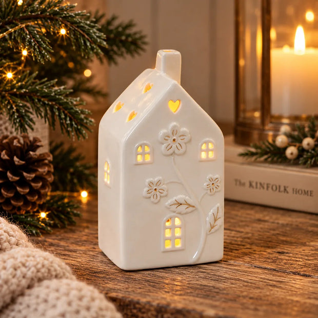 Small ivory ceramic LED house with embossed floral details and heart roof cutouts in a cosy Christmas setting, view 2