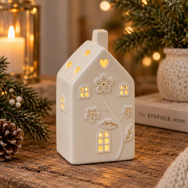 Small ivory ceramic LED house with embossed floral details and heart roof cutouts in a cosy Christmas setting, view 5