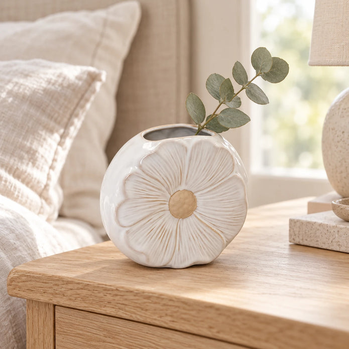 White flower detailed small vase with a eucalyptus sprig on a light oak bedside table