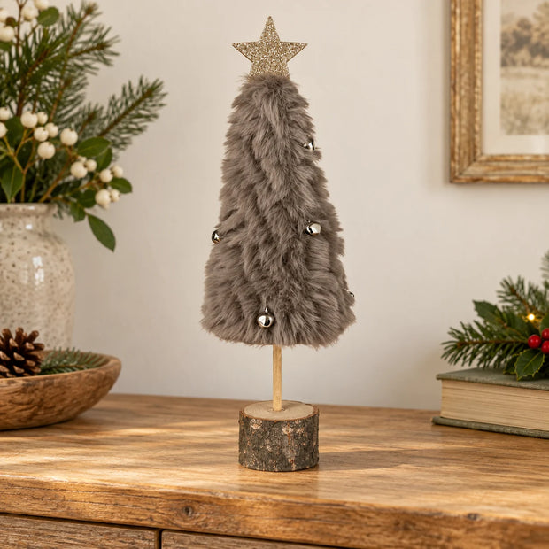 Grey fluffy Christmas tree with bells on an oak console.