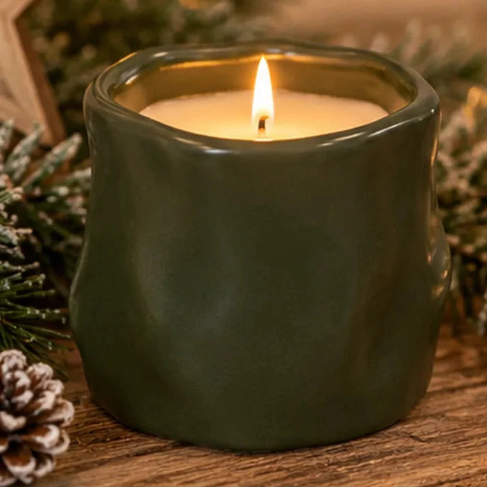 Forest green sculpted candle in a cosy Christmas display with natural pinecones