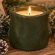 Forest green sculpted candle in a cosy Christmas display with natural pinecones