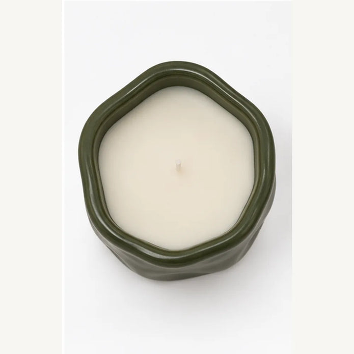 Overhead studio view of forest green sculpted candle showing white wax and central wick