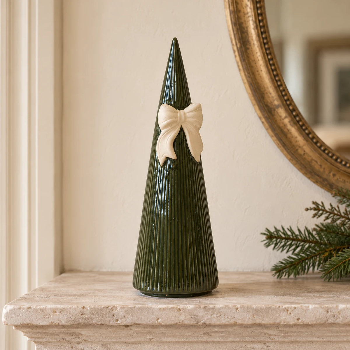 Satchville large forest green striped ceramic Christmas tree with bow displayed on a mantelpiece
