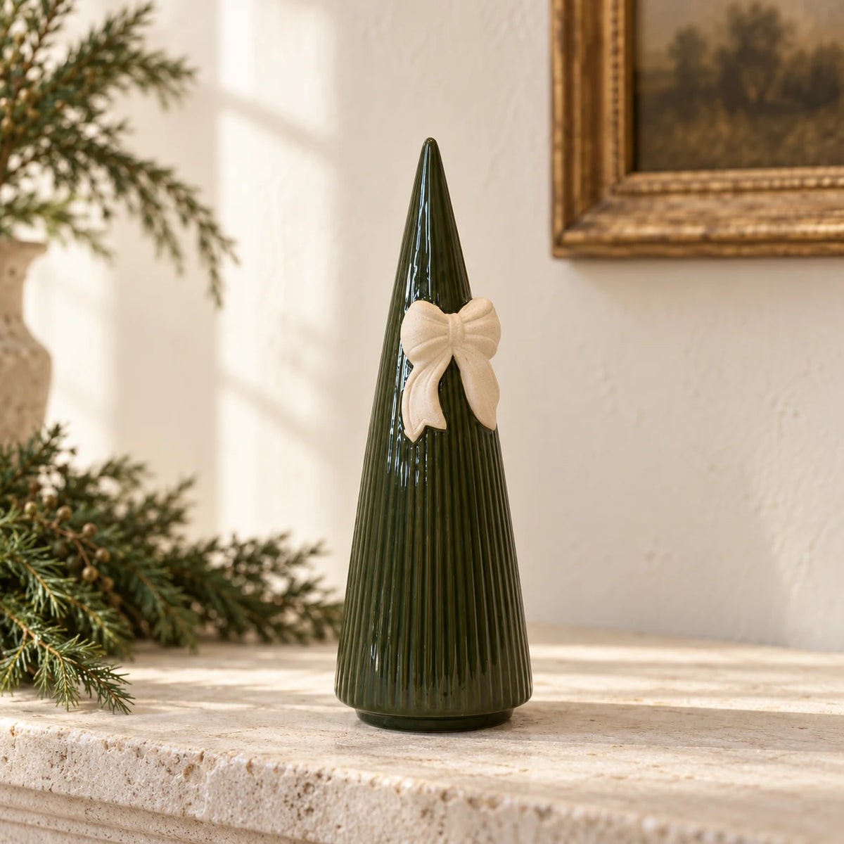 Satchville medium forest green striped ceramic Christmas tree with bow displayed on a mantelpiece