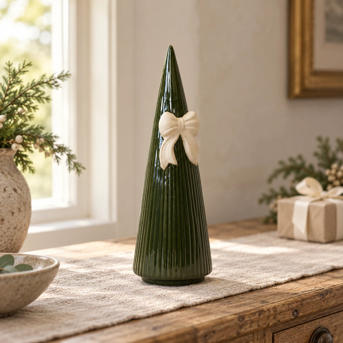 Satchville medium forest green striped ceramic Christmas tree with bow on a styled table