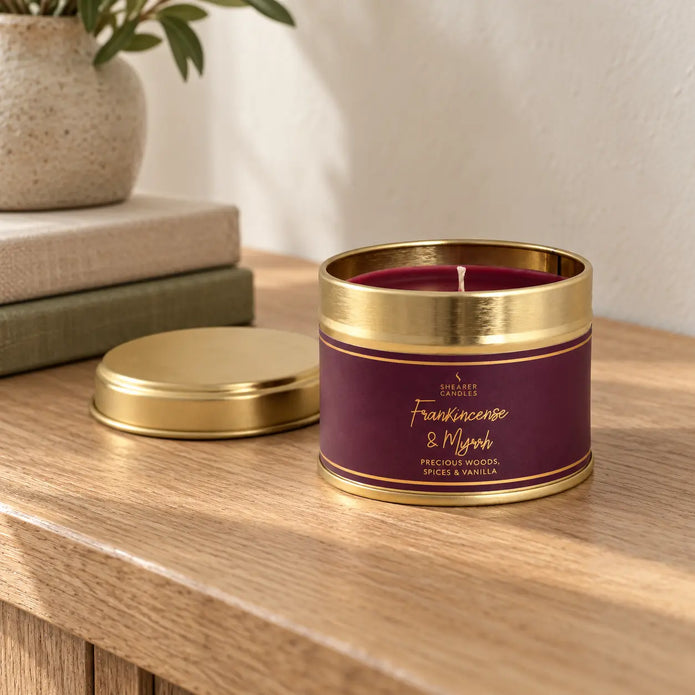 Small tin candle with frankincense and myrrh scent, perfect for Christmas, by Shearer Candles, displayed on a console table.