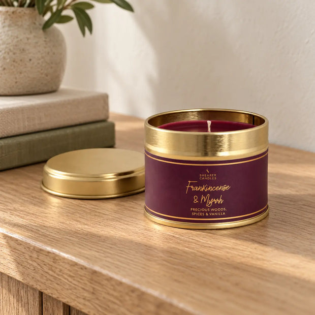 Unlit Shearer Frankincense and Myrrh small tin candle with gold lid on an oak console.