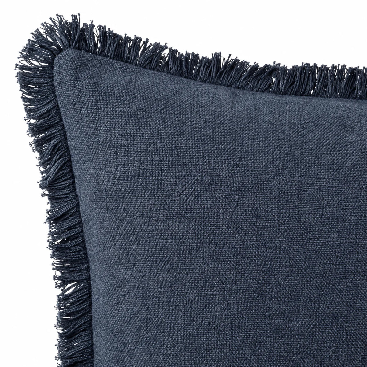 Close-up of a navy blue cushion corner showing the narrow frayed fringe and stitched edge on white.