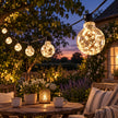 Galaxy Firefly festoon bulbs glowing above an outdoor seating area at dusk.