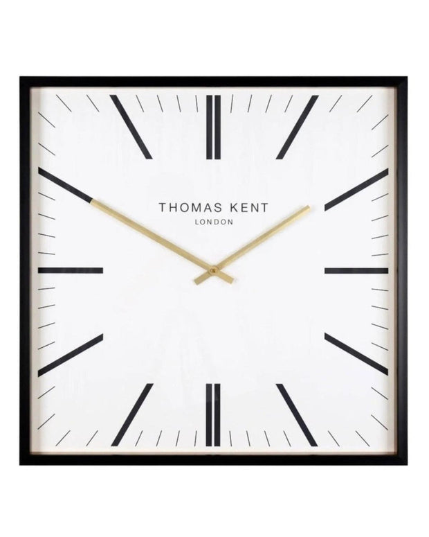 White Thomas Kent Garrick 16-inch wall clock with black Roman numerals and hands, mounted on a plain wall.