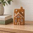 Small gingerbread glazed LED house, unlit on an oak console beside books.