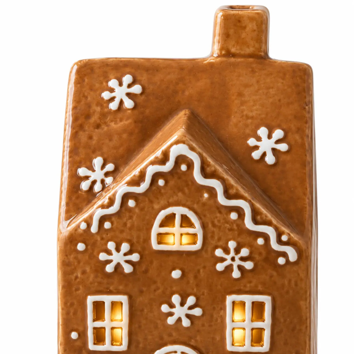 Close-up of the gingerbread house roof, white decorative details and illuminated windows.