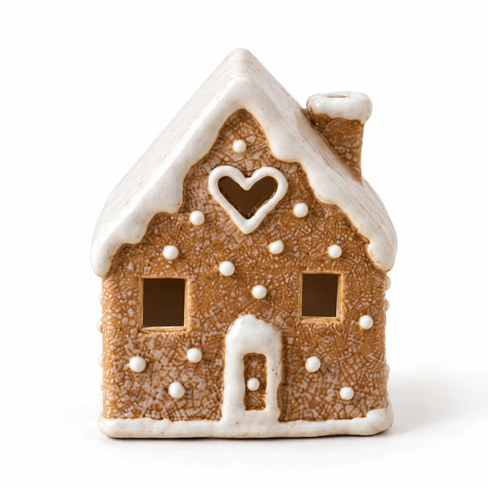 Heart-window gingerbread house tealight holder with white icing details on a white background