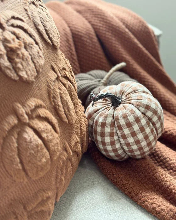 Plush pumpkin with checkered pattern on a textured surface
