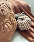 Plush pumpkin with checkered pattern on a textured surface