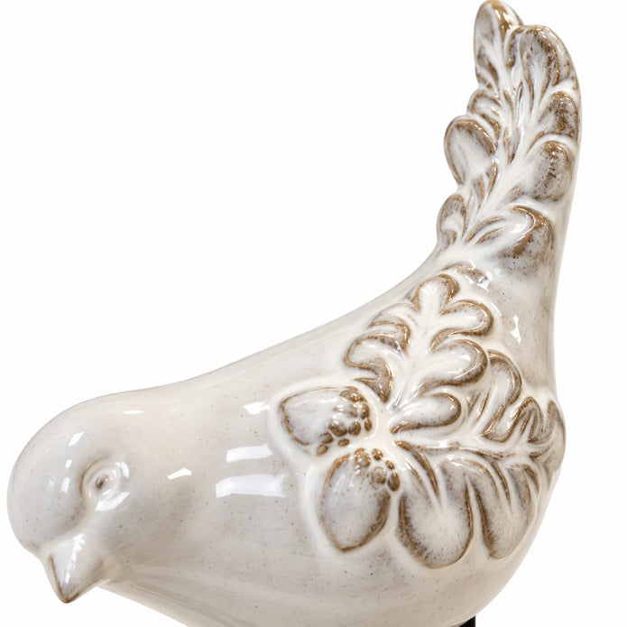 Close-up of the ceramic bird ornament's raised feather pattern and glossy ivory glaze