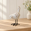 Glazed ceramic bird ornament with textured feathers and black metal feet on a light oak console