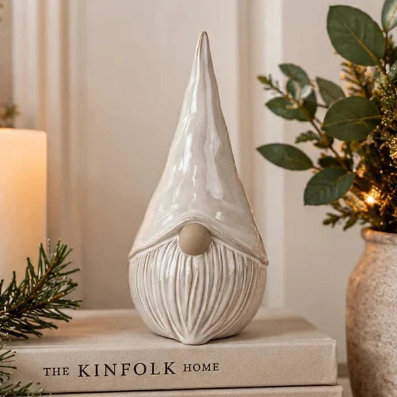 Glossy white ceramic gonk with pointy hat and carved beard styled on books in Christmas home
