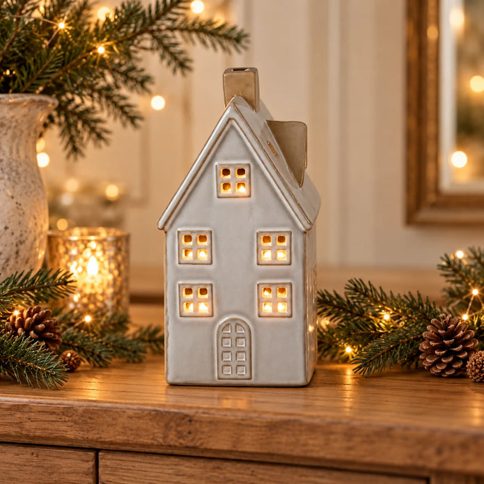 Glazed ceramic LED house glowing on an oak console