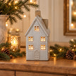 Glazed ceramic LED house glowing on an oak console