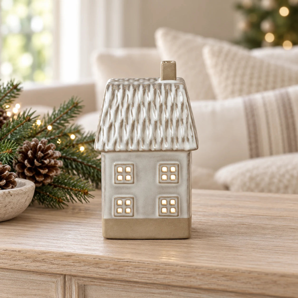 Glazed ceramic LED house with textured roof on an oak console with Christmas greenery