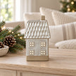 Glazed ceramic LED house with textured roof on an oak console with Christmas greenery
