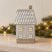 Illuminated ceramic house ornament on a limestone mantel with pine garland
