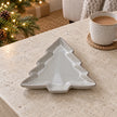 Glazed ceramic tree dish lying flat, on a stone coffee table beside tea
