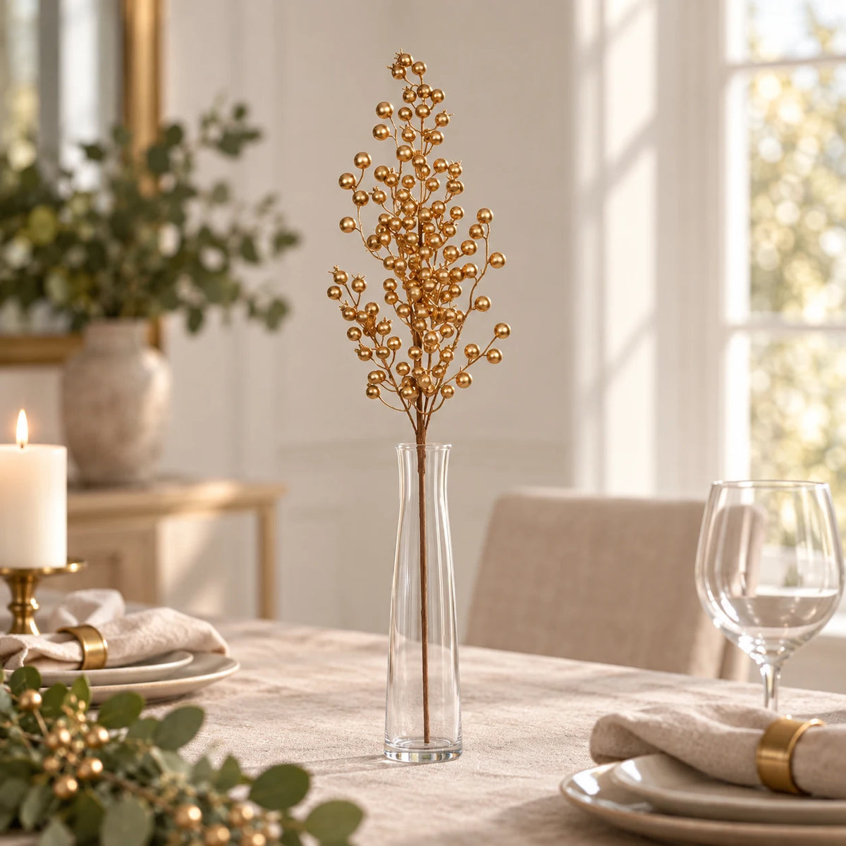 Gold Berries stem in a clear vase on a linen-covered dining table.