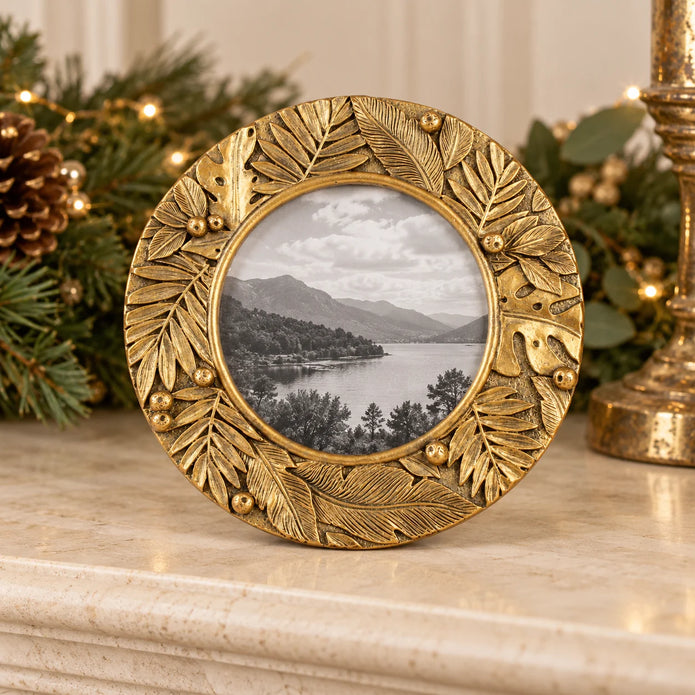 Gold Leaf Botanical round photo frame by Originals International Ltd on a mantelpiece