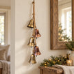 Gold and copper five-bell garland hanging beside a rustic mirror above a country-style console