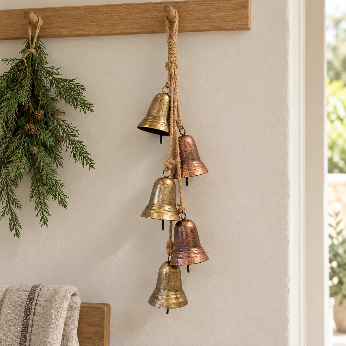 Gold and copper metal bell garland on an oak peg rail with subtle Christmas greenery