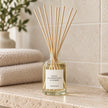 Gold, Frankincense And Myrrh Reed Diffuser styled on a stone bathroom shelf with reeds inserted.