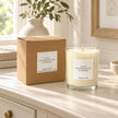 Heaven Scent Gold, Frankincense & Myrrh Medium Candle, unlit with its brown kraft box on a cream console