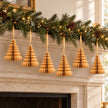 Six gold paper Christmas trees suspended beneath a festive mantel garland.